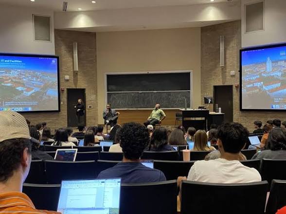 Marqez Bimage speaking from the front of a full university lecture hall at UT Austin